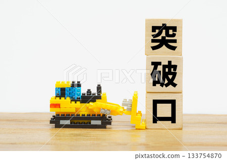 Toy bulldozer cutting a breakthrough in a block wall 133754870
