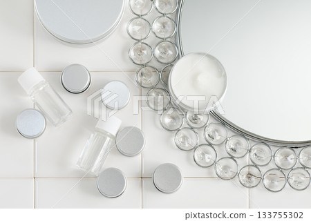 Luxurious mirror and small cosmetic containers lined up on white tiles Luxurious mirror and small cosmetic containers lined up on white tiles 133755302