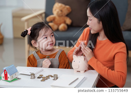 Family Finance. Parent and child discussing savings with piggy bank. Family Finance. Parent and child discussing savings with piggy bank. 133755649