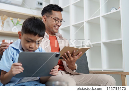 Family Life: Father and son enjoying digital reading together Family Life: Father and son enjoying digital reading together 133755670