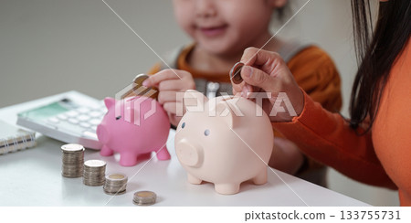 Teaching Saving. Child and parent using piggy banks for financial education. Teaching Saving. Child and parent using piggy banks for financial education. 133755731
