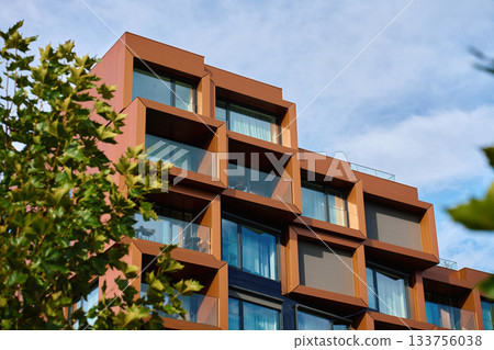 Modern apartment building with geometric balconies and glass facade 133756038
