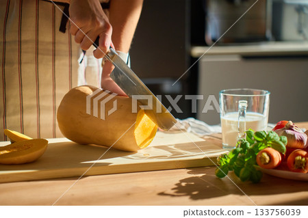 Woman cutting pumpkin on wooden board in kitchen 133756039