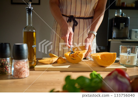 Woman scooping seeds from pumpkin at home kitchen 133756040