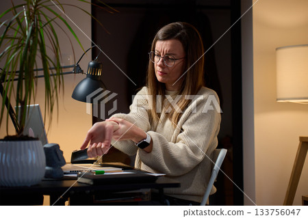 Woman sitting at desk with wrist pain during remote work 133756047