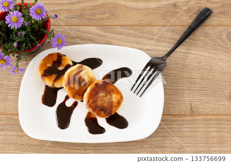 Curd fritters with chocolate on the porcelain plate. Curd fritters with chocolate on the porcelain plate. 133756699