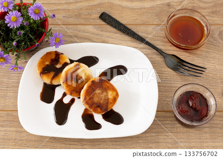Curd fritters with chocolate, strawberry jam and honey. 133756702
