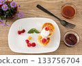 Curd fritters with sour cream, raspberries, strawberry jam and honey. 133756704