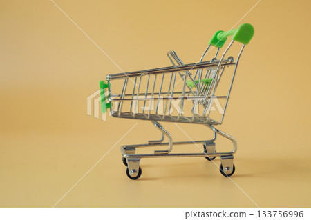An empty tiny shopping cart on color background. An empty tiny shopping cart on color background. 133756996