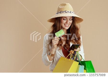 smiling elegant housewife in blouse and shorts against beige 133757009