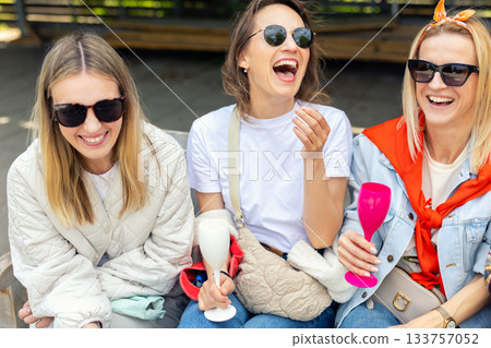 Group happy friends women enjoy sunny outdoor moment talking laughing together outdoors. Warm sunlight creates cheerful atmosphere, highlighting friendship, joy and carefree mood during weekend walk Group happy friends women enjoy sunny outdoor moment talking laughing together outdoors. Warm sunlight creates cheerful atmosphere, highlighting friendship, joy and carefree mood during weekend walk 133757052