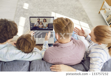 Family with children sitting on sofa using laptop and having online video call with relatives. Family with children sitting on sofa using laptop and having online video call with relatives. 133757232