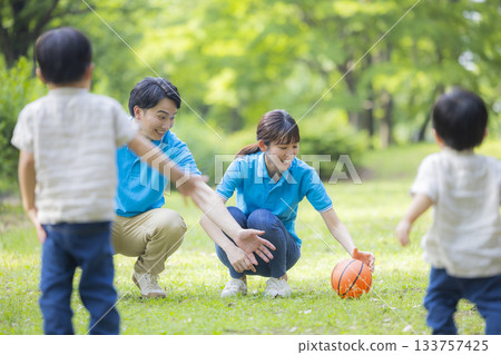 Male and female staff in blue polo shirts playing with children 133757425