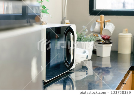 Microwave oven on the table in the kitchen at home. Microwave oven on the table in the kitchen at home. 133758389
