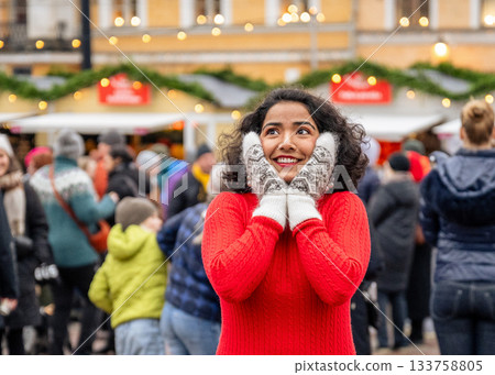indian woman in winter mittens and red sweater standing at christmas market in helsinki indian woman in winter mittens and red sweater standing at christmas market in helsinki 133758805