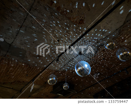 Disco ball spins on ceiling, illuminating dark space with its rays. Dance backdrop for project related to nightlife and dancing in venue. Nightlife news and article Disco ball spins on ceiling, illuminating dark space with its rays. Dance backdrop for project related to nightlife and dancing in venue. Nightlife news and article 133759447