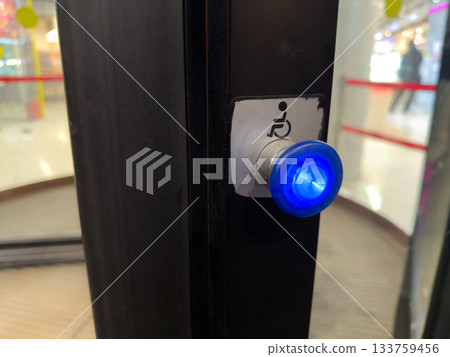 Accessibility features at building entrance. Button to slow down revolving door. Assisting wheelchair users with button at entrance to building with revolving doors Accessibility features at building entrance. Button to slow down revolving door. Assisting wheelchair users with button at entrance to building with revolving doors 133759456