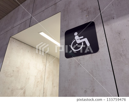 Sign at entrance to accessible restroom. Hallway with directions to accessible WC. Hygiene for people with disabilities. Creating special restroom with amenities for wheelchair users Sign at entrance to accessible restroom. Hallway with directions to accessible WC. Hygiene for people with disabilities. Creating special restroom with amenities for wheelchair users 133759476