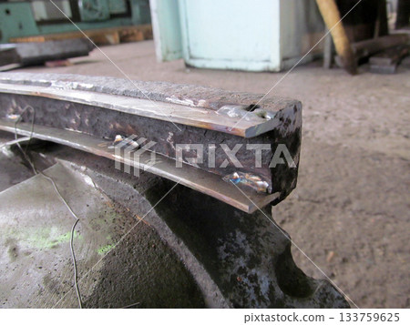 Close-up of a metal component with visible welding spots, suggesting repair or fabrication. The rough, textured surface of the metal. Industrial setting. Restoration of diaphragms Close-up of a metal component with visible welding spots, suggesting repair or fabrication. The rough, textured surface of the metal. Industrial setting. Restoration of diaphragms 133759625