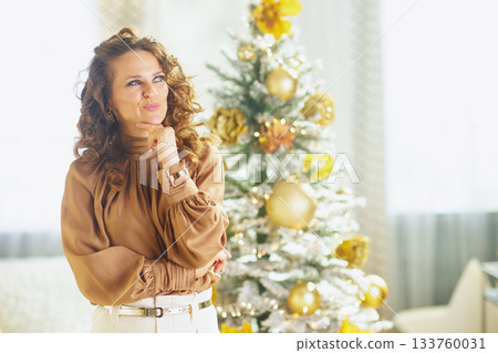 Thoughtful Woman Reflects by a Festive Christmas Tree 133760031