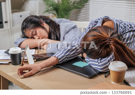 Young business team women work online at home office, tired people sleep on desk, showing burnout from demanding tasks, colleagues exhausted after long hours completing important business projects. Young business team women work online at home office, tired people sleep on desk, showing burnout from demanding tasks, colleagues exhausted after long hours completing important business projects. 133760091