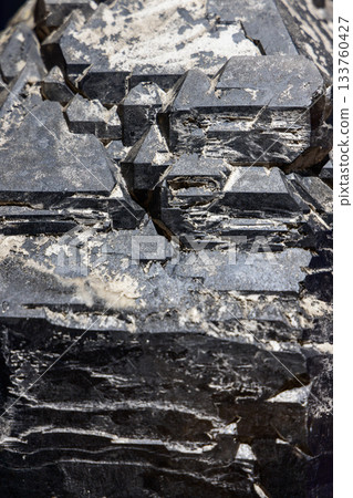 Black tourmaline closeup displays prismatic mineral form with sharp edges and matte crystal texture 133760427