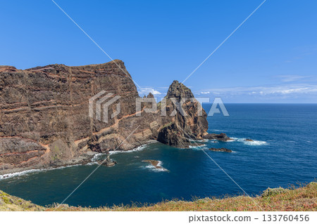 Towering cliffs at Ponta de Sao Lourenco Madeira rise above bay with rocky layers and soft plants Towering cliffs at Ponta de Sao Lourenco Madeira rise above bay with rocky layers and soft plants 133760456