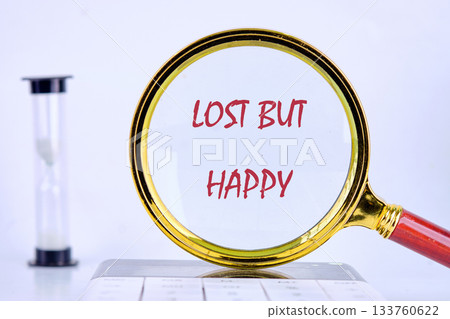 A person finds happiness in the phrase lost but happy while looking through a magnifying glass in a peaceful workspace with an hourglass nearby A person finds happiness in the phrase lost but happy while looking through a magnifying glass in a peaceful workspace with an hourglass nearby 133760622