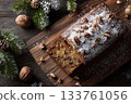 Delicious fruitcake topped with powdered sugar and nuts served on a wooden board 133761056
