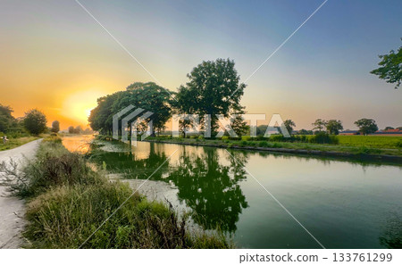 Serene countryside sunset with reflective trees and gentle mist Serene countryside sunset with reflective trees and gentle mist 133761299