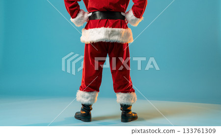 Santa Claus figure standing against a blue background wearing a red suit and black boots ready for festive celebrations 133761309