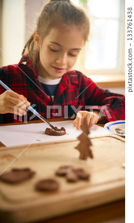 Girl painting clay figure with small brush during art practice Girl painting clay figure with small brush during art practice 133761438