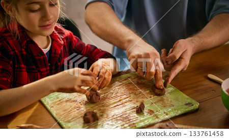 Child and father shaping clay together on homework board 133761458