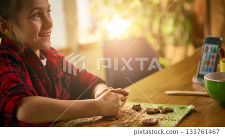 Girl smiling while shaping small clay pieces at table Girl smiling while shaping small clay pieces at table 133761467