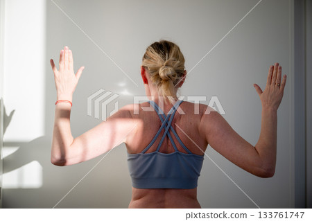 woman practicing shoulder mobility exercise at home in sports bra woman practicing shoulder mobility exercise at home in sports bra 133761747