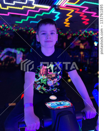 Boy playing arcade game under neon lights 133761895