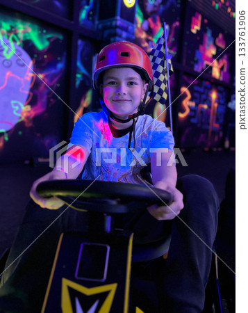 Boy enjoying glow kart racing with checkered flag Boy enjoying glow kart racing with checkered flag 133761906