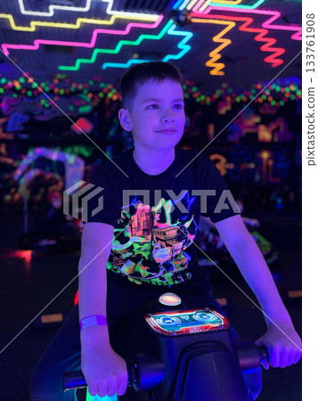 Boy playing video game in neon lit arcade 133761908