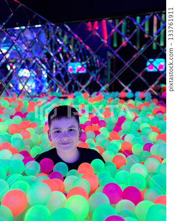 Happy boy playing in glowing neon ball pit Happy boy playing in glowing neon ball pit 133761911