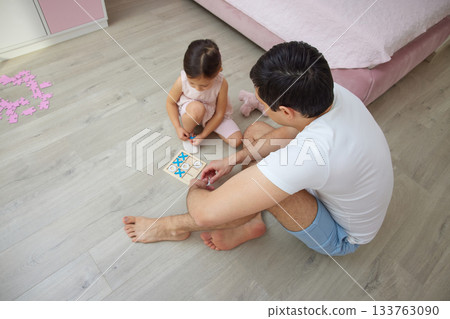 Father and daughter enjoying quality time playing a tic-tac-toe board game on the floor Father and daughter enjoying quality time playing a tic-tac-toe board game on the floor 133763090
