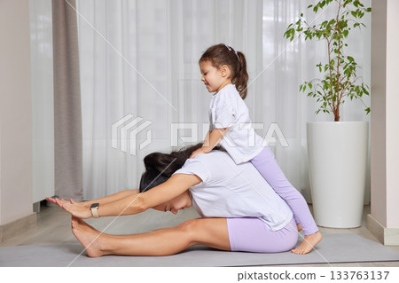 Mother and daughter bonding during a playful yoga session on a mat 133763137
