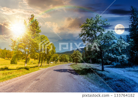 old road through forest in mountains. day and night time change concept. summer landscape with clouds above the distant ridge with sun and moon. beech trees along the path. equality and shift template 133764182