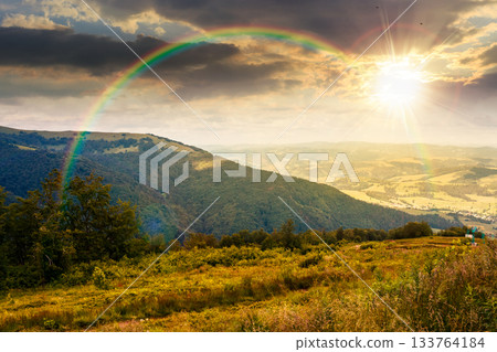 mountain landscape under blue sky with clouds at sunset. countryside scenery with green meadow, rolling hills and valley in evening light. hiking place in summer. storytelling image under the rainbow 133764184