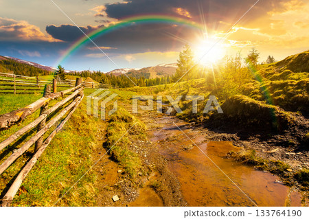 rural scene of mountain landscape in spring at sunset. green countryside with forested hills in evening light. beautiful valley sustainable development under rainbow 133764190