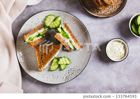 Cucumber sandwich with butter and cream cheese on a plate on the table top view 133764593