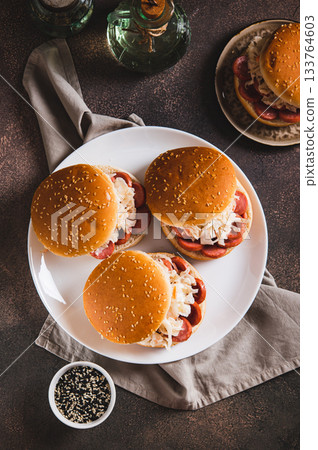 Burgers with grilled sausage and coleslaw on a plate top and vertical view Burgers with grilled sausage and coleslaw on a plate top and vertical view 133764603