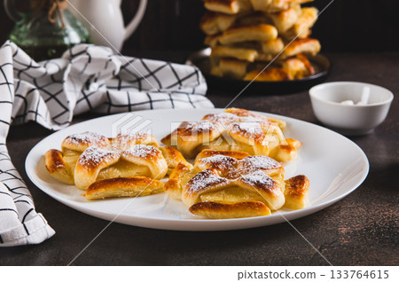 Sweet puff pastries with pineapple in powdered sugar on the table 133764615