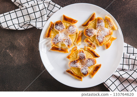 Close up of sweet puff pastries with pineapple in powdered sugar on the table top view 133764620