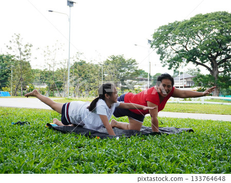 Mother and Daughter Practicing Yoga and Stretching Outdoors on Grass Mother and Daughter Practicing Yoga and Stretching Outdoors on Grass 133764648