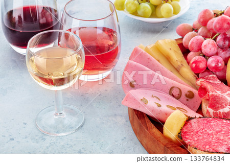 Italian Antipasti with wine glasses and fruit. Charcuterie platter with Bologna Italian Antipasti with wine glasses and fruit. Charcuterie platter with Bologna 133764834